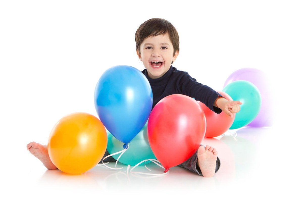 Criança sorrindo cercada de balões coloridos